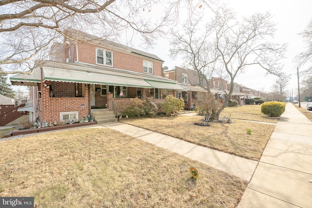 view of front facade featuring a front lawn, a porch, and brick siding