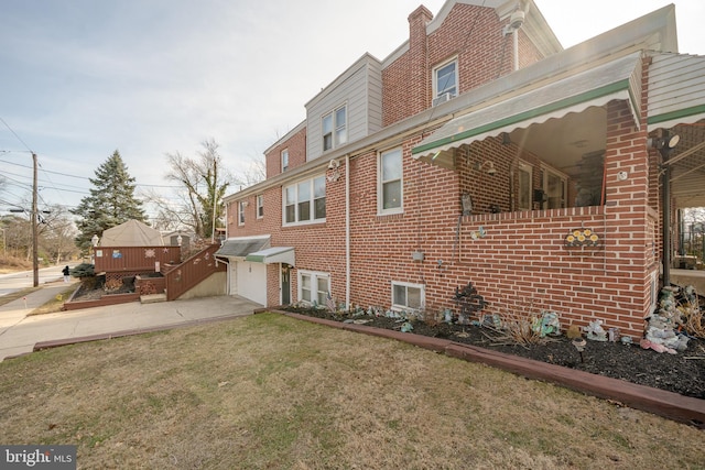 view of side of home featuring concrete driveway, a yard, brick siding, and an attached garage