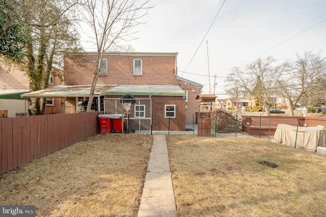 rear view of house with a gate, brick siding, a yard, and fence