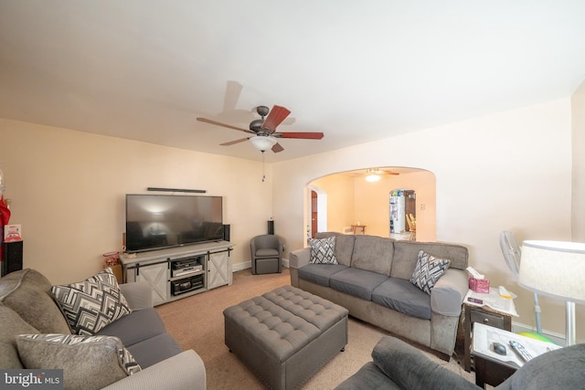 living room featuring ceiling fan, baseboards, arched walkways, and light carpet