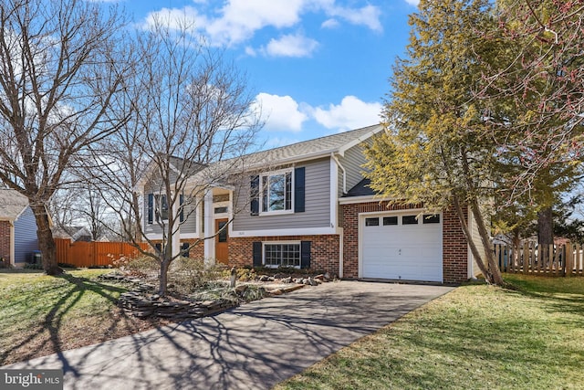 bi-level home featuring a garage, aphalt driveway, fence, a front lawn, and brick siding