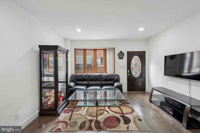 living area with baseboards, wood finished floors, and recessed lighting