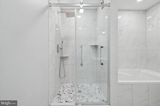 bathroom with a marble finish shower and a bath