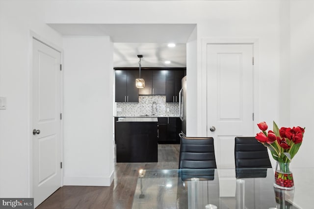 kitchen with pendant lighting, light countertops, decorative backsplash, a sink, and dark cabinets