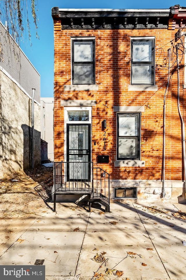 view of front of home featuring brick siding and a patio