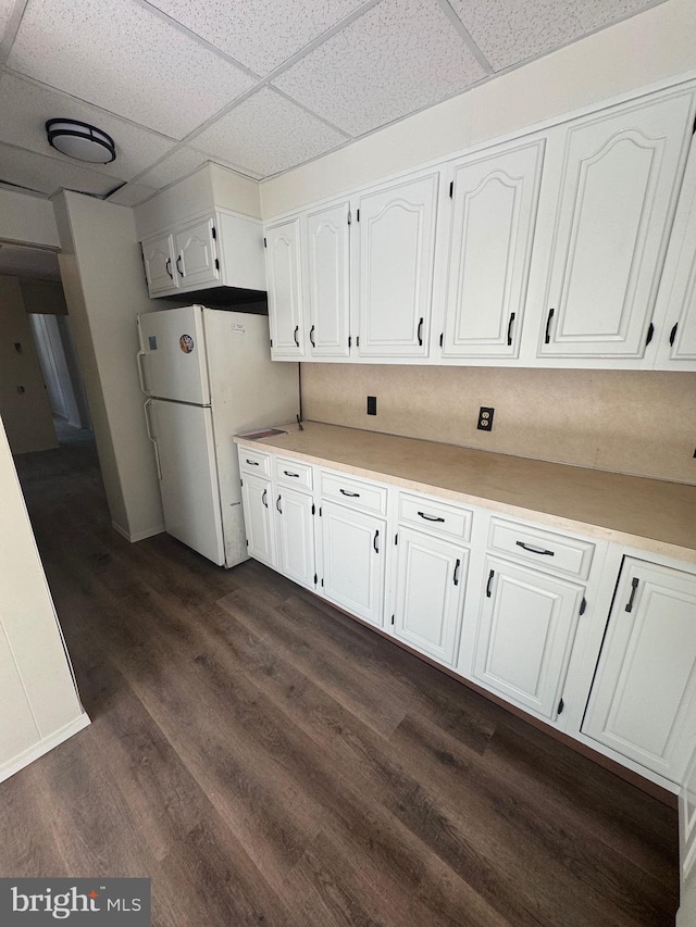 kitchen with a paneled ceiling, white cabinetry, light countertops, freestanding refrigerator, and dark wood-style floors