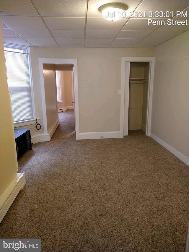 unfurnished bedroom featuring a closet, a drop ceiling, carpet flooring, and baseboards