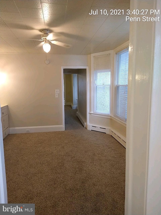 carpeted spare room with ceiling fan and baseboards