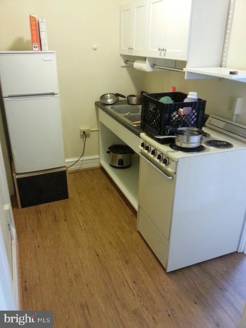 kitchen featuring light wood-type flooring, white appliances, and white cabinets