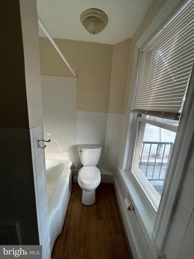 full bathroom featuring wainscoting, tile walls, toilet, and wood finished floors