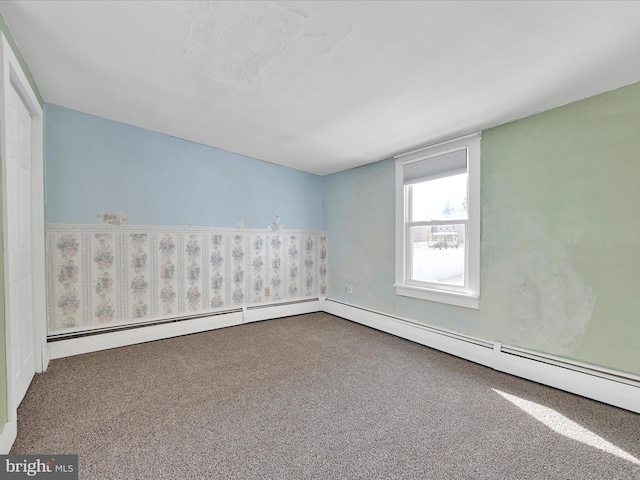 unfurnished room with a baseboard heating unit and carpet