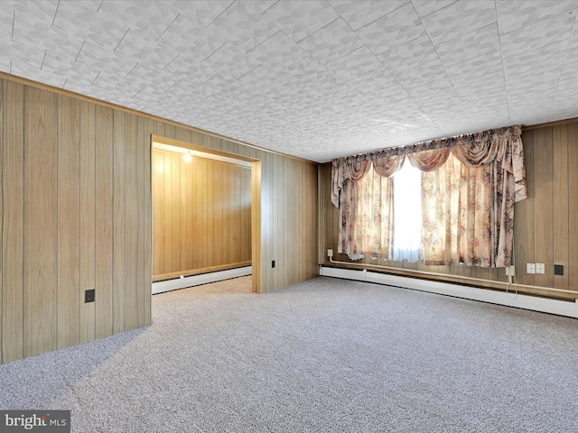 carpeted empty room with baseboard heating, a baseboard radiator, and wooden walls