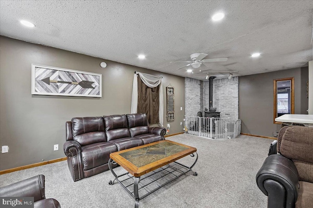 carpeted living room featuring a textured ceiling, ceiling fan, a wood stove, and baseboards