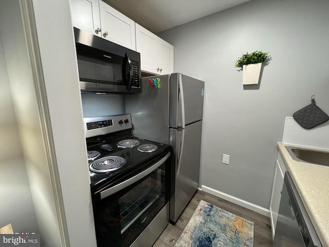 kitchen with electric stove, light countertops, dark wood-type flooring, white cabinets, and baseboards