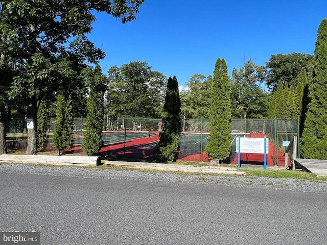 exterior space featuring a tennis court and fence