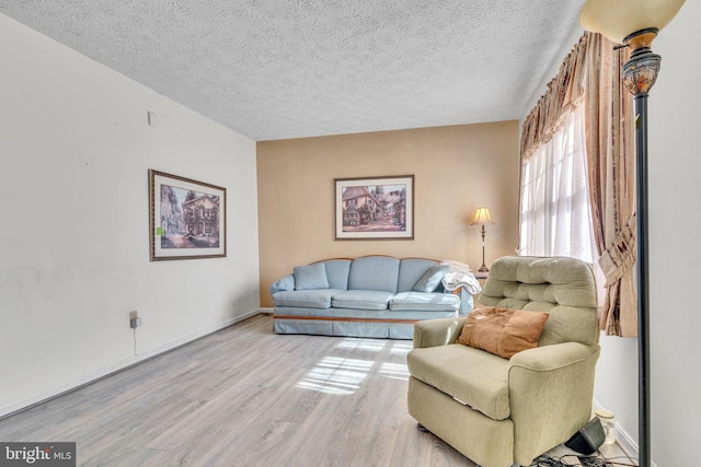 living room featuring a textured ceiling, wood finished floors, and baseboards