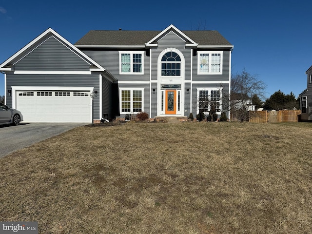 view of front of house with driveway, an attached garage, fence, and a front lawn