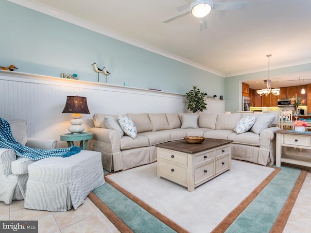 living area with ceiling fan with notable chandelier, ornamental molding, and light tile patterned flooring