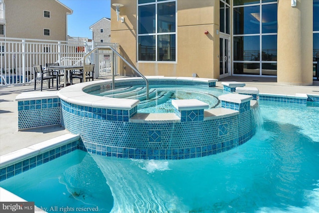 view of pool with a pool with connected hot tub and fence