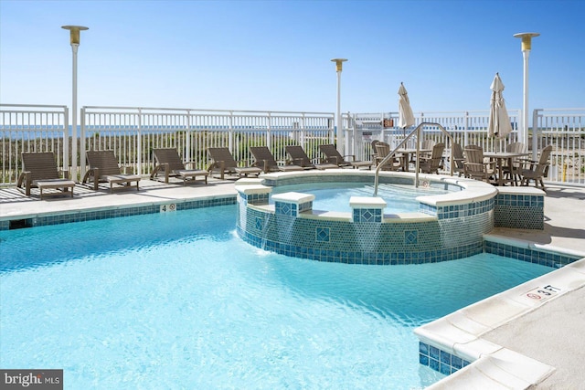 view of swimming pool featuring a patio area, fence, and a pool with connected hot tub