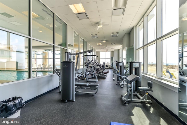 exercise room with a drop ceiling, visible vents, and a healthy amount of sunlight