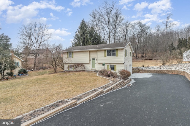 split foyer home with an attached garage, driveway, and a front yard