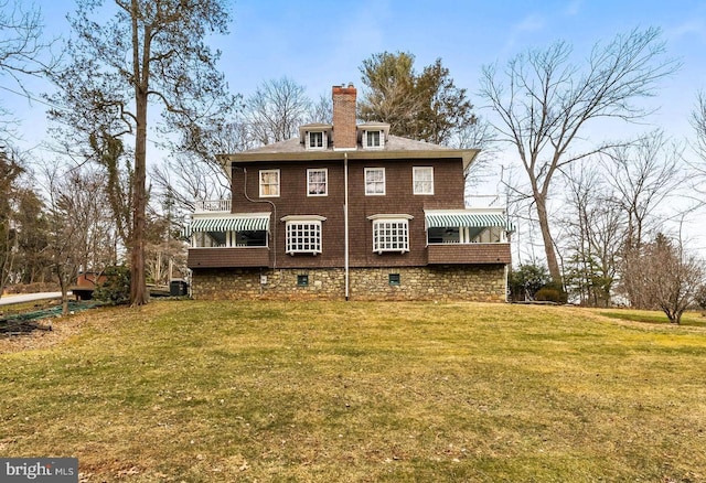 back of property featuring a chimney, cooling unit, and a yard