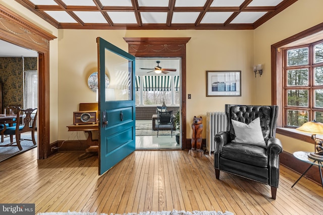 living area with radiator, hardwood / wood-style flooring, baseboards, and coffered ceiling