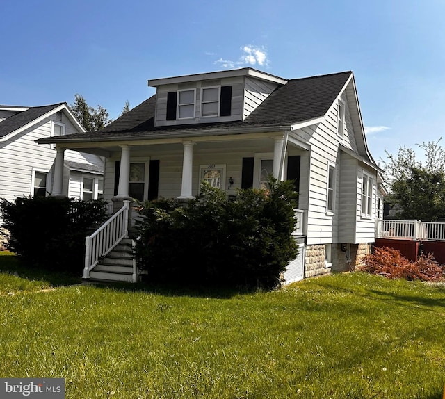 bungalow featuring covered porch, a front lawn, and a shingled roof
