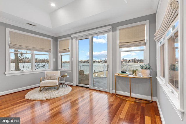 interior space with crown molding, wood-type flooring, visible vents, and baseboards