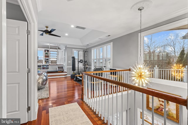 hall with a chandelier, ornamental molding, wood finished floors, and visible vents