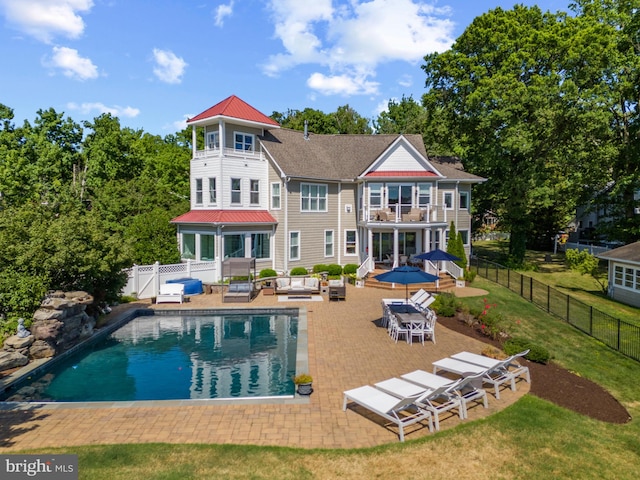 rear view of house featuring a fenced in pool, a lawn, a patio area, a balcony, and a fenced backyard