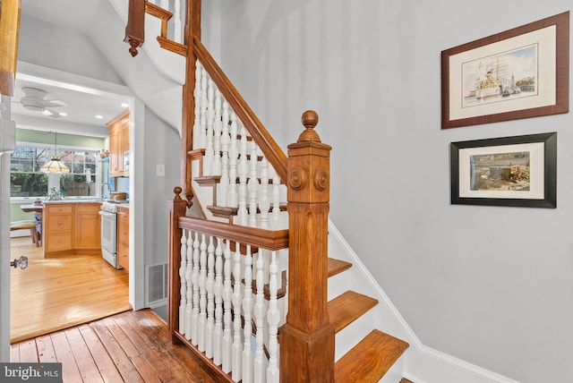 stairs with baseboards, visible vents, and wood finished floors