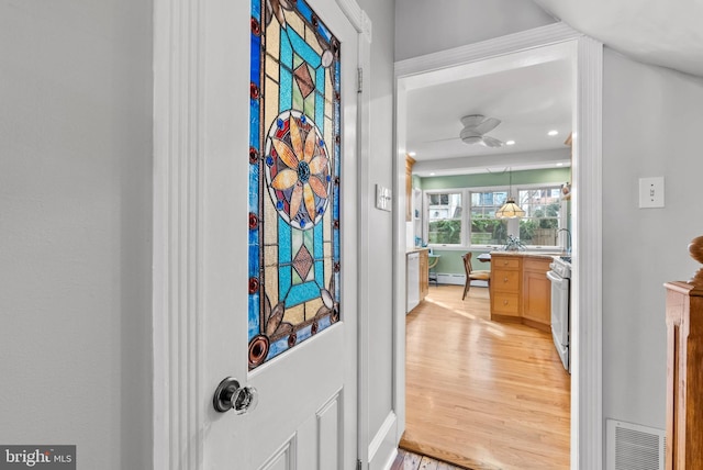 doorway featuring recessed lighting, visible vents, light wood-style floors, a baseboard heating unit, and a sink