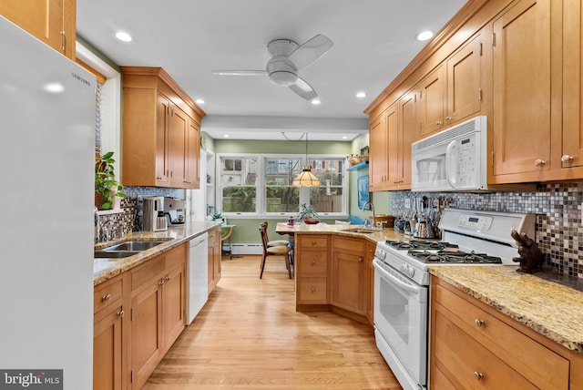 kitchen featuring white appliances, light wood-style floors, pendant lighting, and a sink