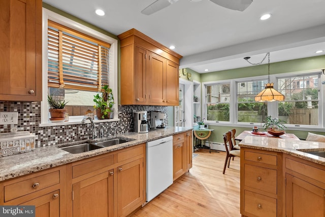 kitchen featuring dishwasher, a sink, light stone countertops, and pendant lighting