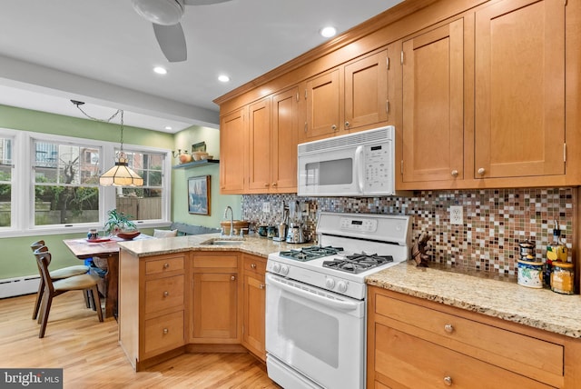 kitchen featuring white appliances, decorative light fixtures, a peninsula, light wood-style floors, and a sink