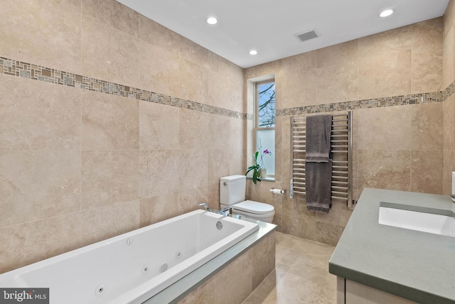 full bath featuring toilet, visible vents, vanity, tile walls, and a whirlpool tub