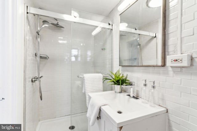 full bath with vanity, a shower stall, and tile walls