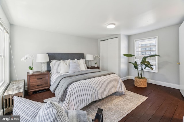 bedroom featuring a closet, radiator, baseboards, and hardwood / wood-style flooring