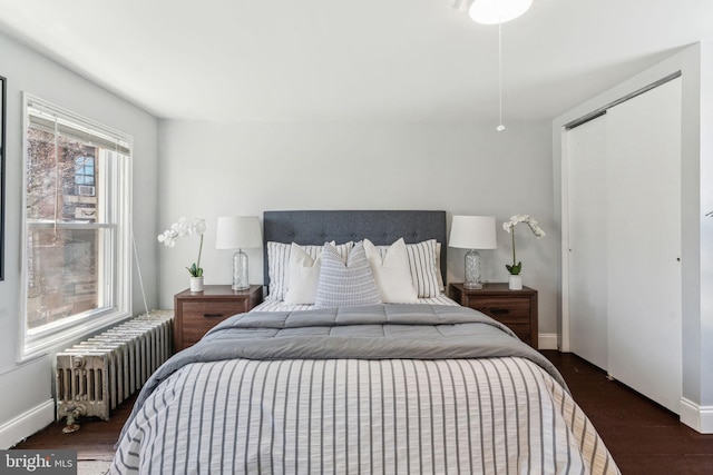 bedroom featuring radiator heating unit, wood finished floors, a closet, and baseboards