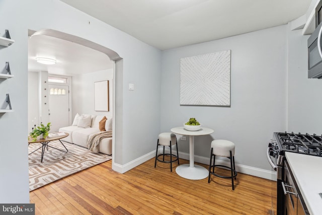 living area featuring baseboards, arched walkways, and wood-type flooring