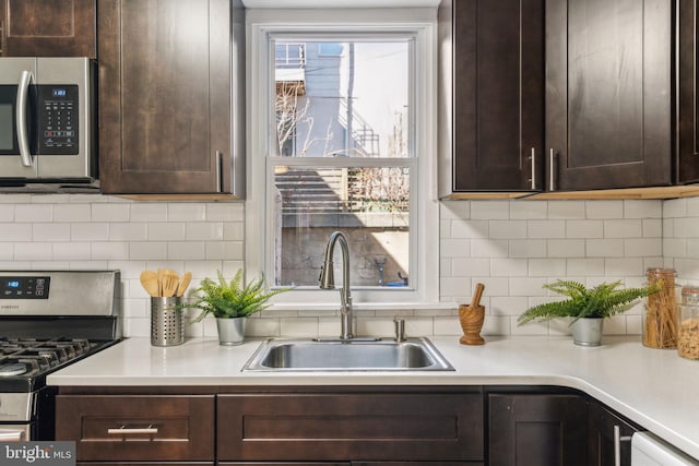 kitchen featuring dark brown cabinetry, light countertops, appliances with stainless steel finishes, and a sink