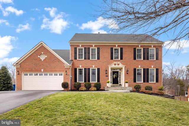 view of front of home with aphalt driveway, a front yard, brick siding, and an attached garage