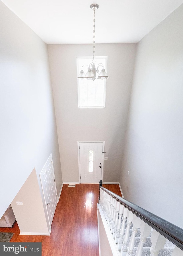 entryway with baseboards, visible vents, dark wood-type flooring, stairs, and a chandelier