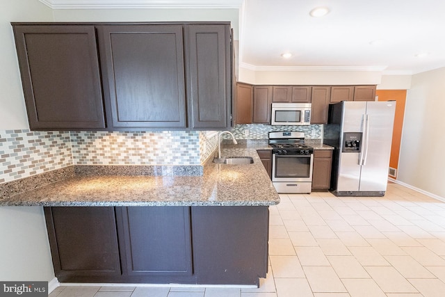 kitchen with appliances with stainless steel finishes, stone countertops, a sink, and ornamental molding