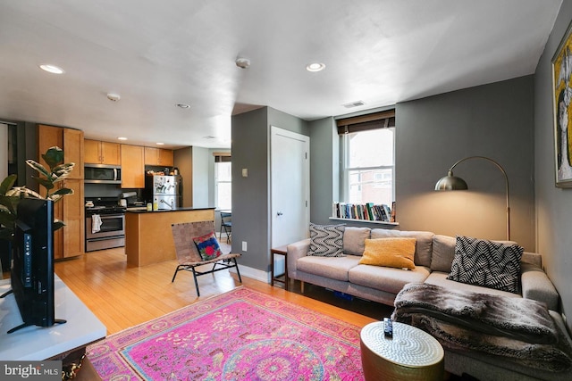 living room with light wood-type flooring, baseboards, visible vents, and recessed lighting