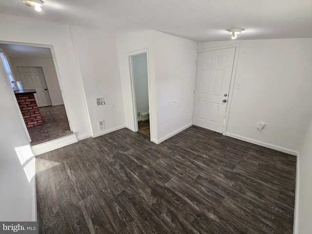 unfurnished room featuring dark wood-type flooring, visible vents, and baseboards