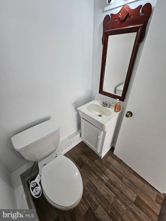 half bathroom featuring toilet, wood finished floors, and vanity