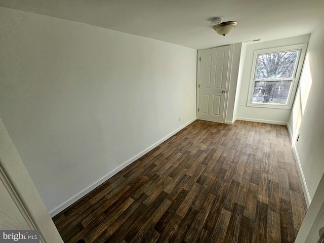 empty room with dark wood-type flooring and baseboards